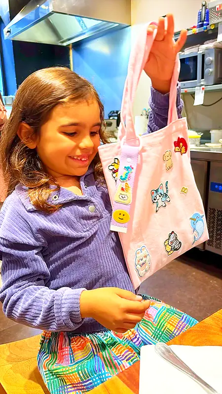 Une petite cliente montre fièrement son tote bag rose couvert d'écussons