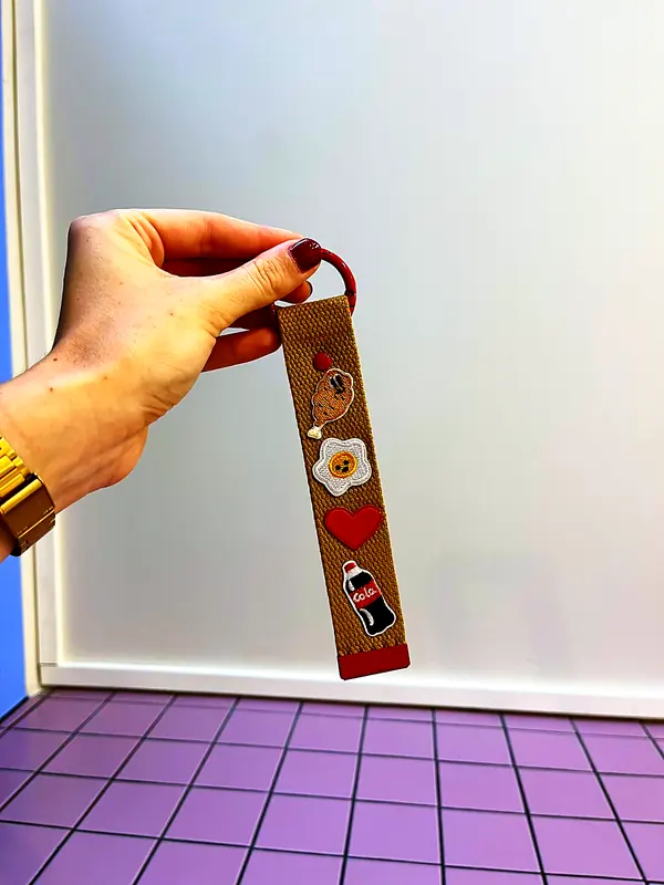 Porte-clés kaki personnalisé tenu à la main devant le mur de la boutique