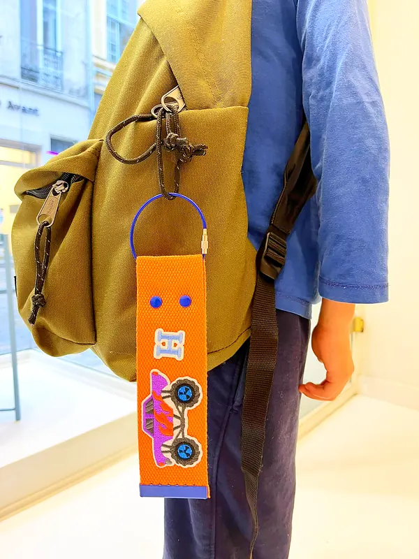 Porte-clés orange à écussons accroché à un sac à dos